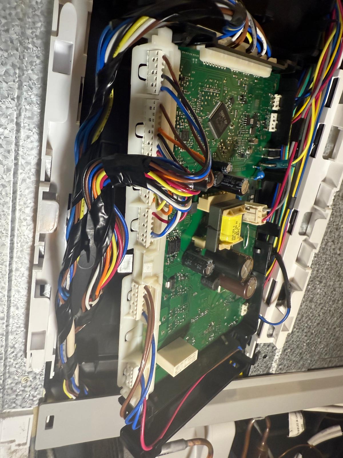 Appliance main control board with wiring harness during repair
