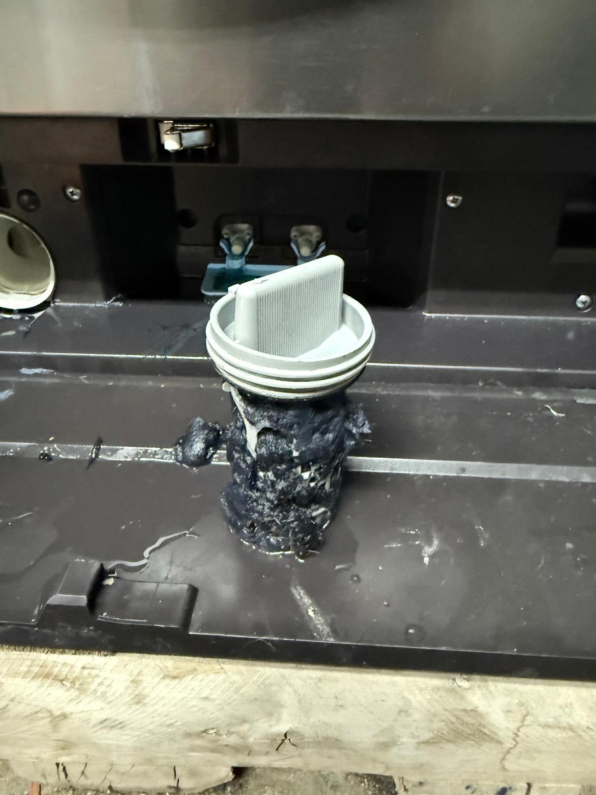 Drain filter housing with debris buildup inside a dishwasher base