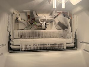 Freezer evaporator coil covered in heavy frost and ice buildup