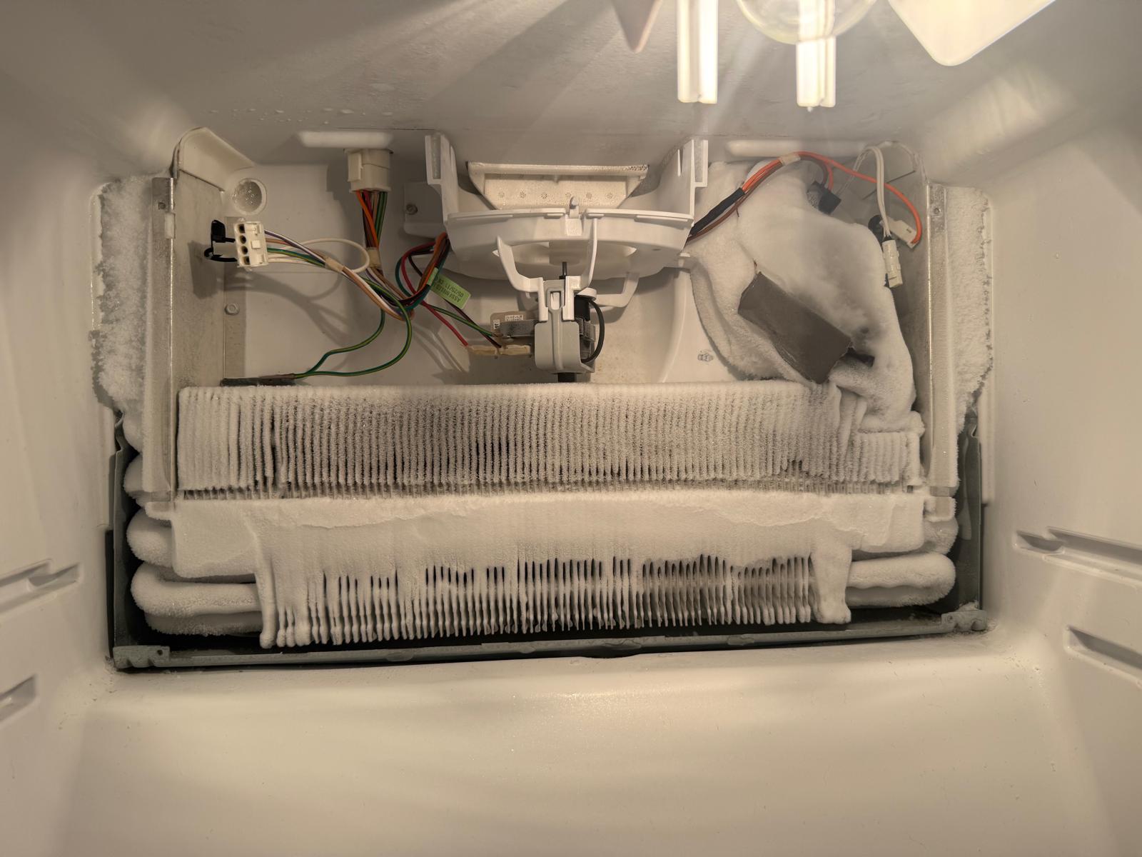 Freezer evaporator coil covered in heavy frost and ice buildup