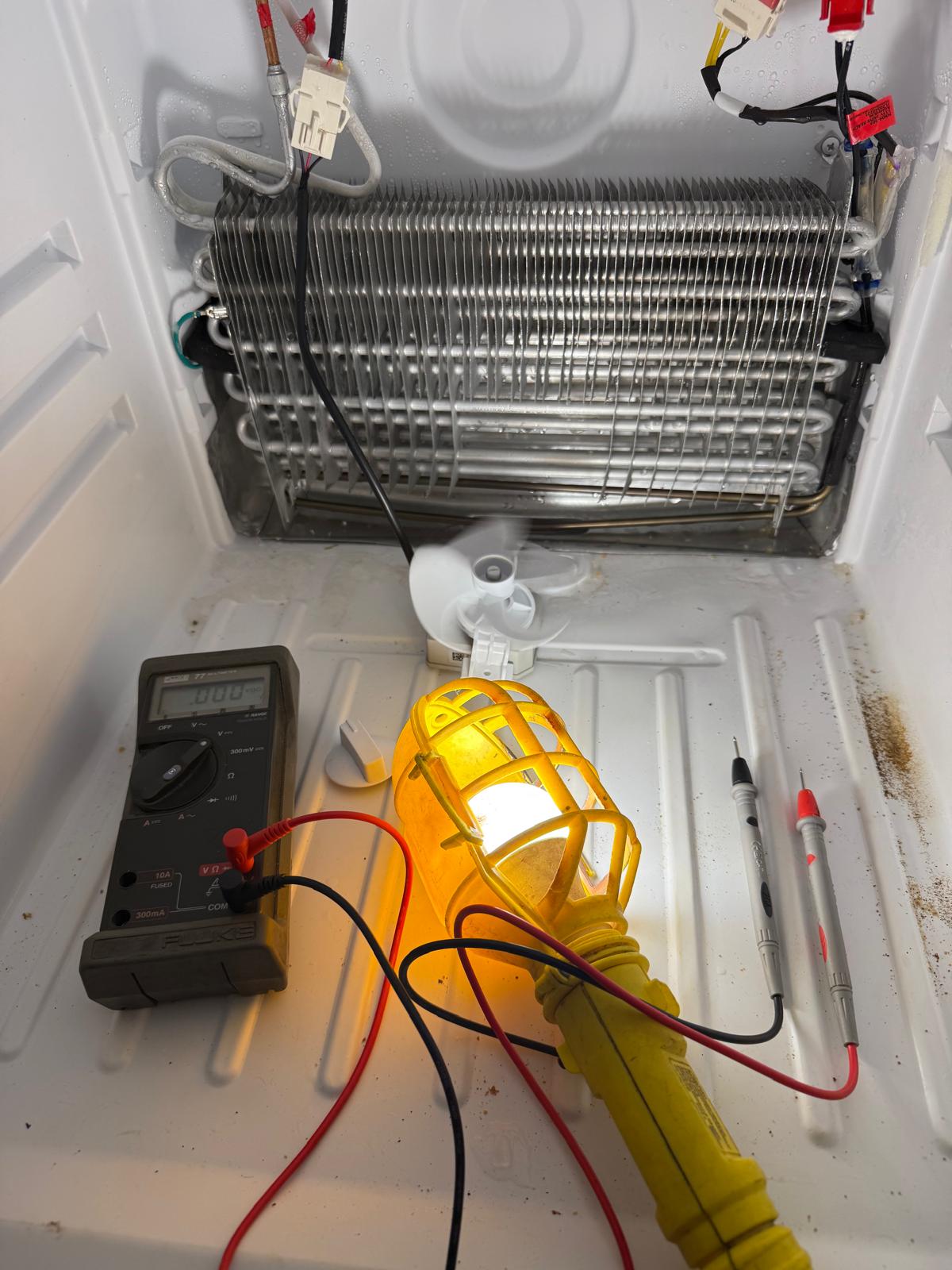 Freezer evaporator coil tested with multimeter during repair