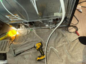 Underside of appliance with wiring and tools laid out for service